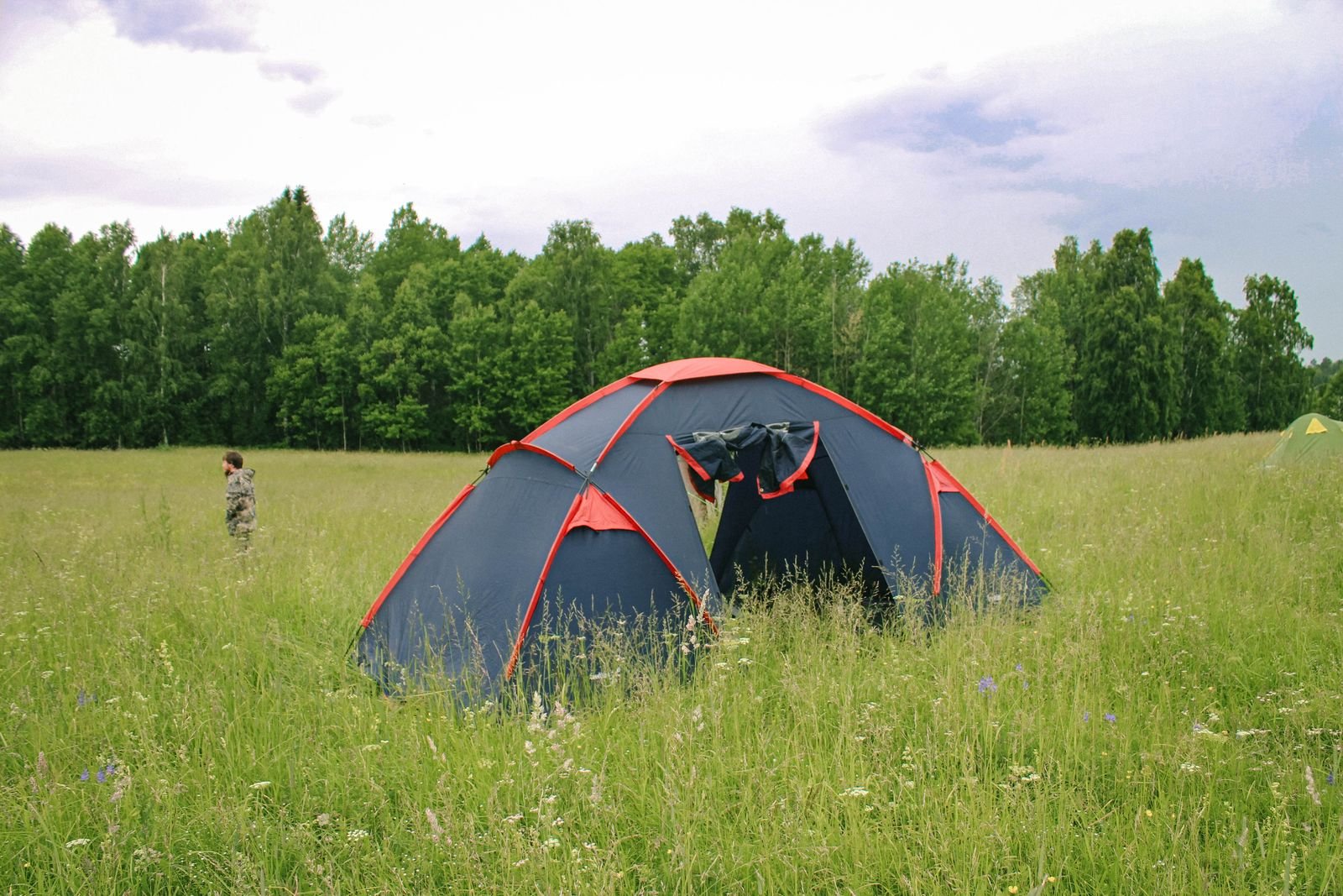 Zelt auf einer grünen Wiese am Waldrand — typische Minicamping-Atmosphäre