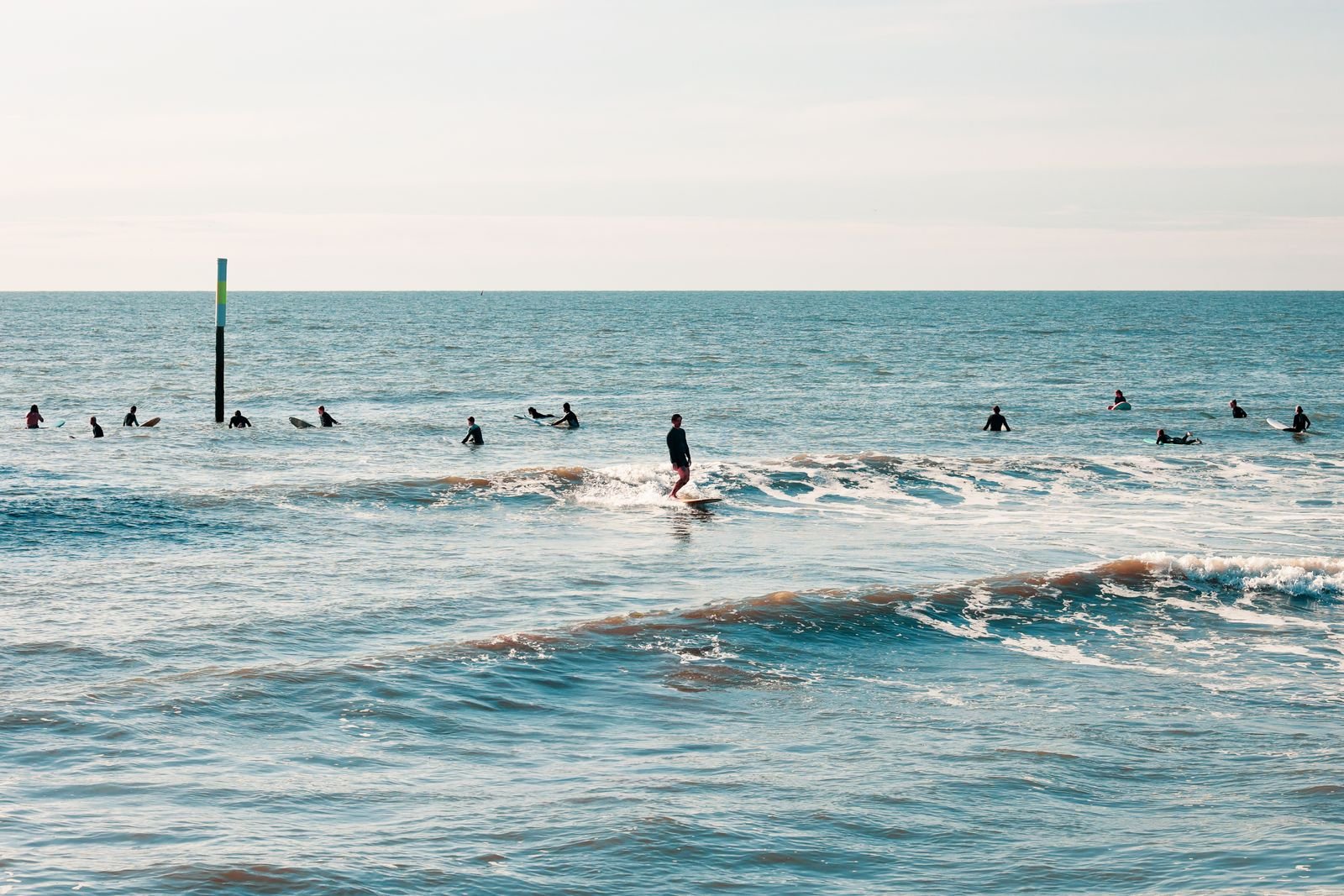 Surfer in Neoprenanzügen in den kleinen Wellen der Nordsee — ideale Lernbedingungen